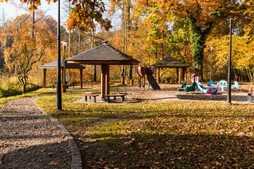 Modern, wooden roof covered with shingles, protection against rain and sun in the park. The middle of golden autumn.