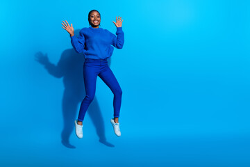 Photo of charming excited woman wear sweatshirt jumping high empty space isolated blue color background