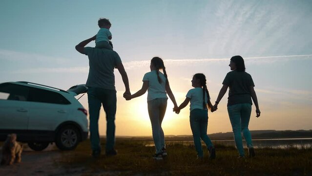 people in the park. happy family a silhouette walk at sunset. car travel kid dream concept. happy family parents and fun sun children walk silhouette next to car. family walk next to car