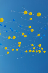 Blue and yellow balloons on blue sky background