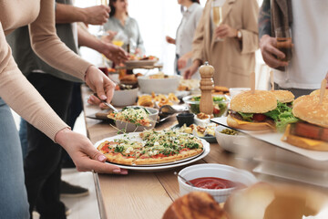 Woman taking slice of pizza from buffet indoors, closeup. Brunch table setting