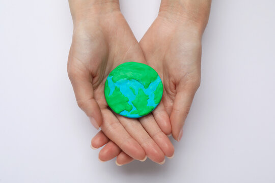 Woman holding plasticine model of planet on white background, top view. Earth Day