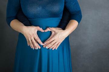9 miesięcy ciąży, kobieta i mężczyzna trzymają ręce w kształcie serca na brzuchu ciążowym - obrazy, fototapety, plakaty