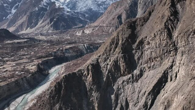 Pakistani trucks travel on dangerous paved road along the mountain, transport goods via Karakoram highway. Gilgit Baltistan, Pakistan.
