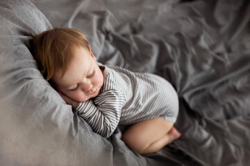 Mały chłopiec śpi na łóżku jak mały bobas - obrazy, fototapety, plakaty