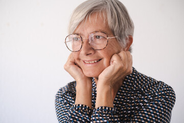 Close up portrait of beautiful elderly woman wearing glasses looking away smiling pensive. Short haired caucasian lady feeling in a good mood
