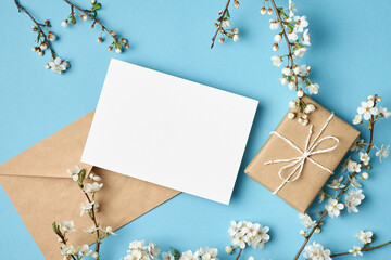 Greeting card mockup with gift and white flowers on blue