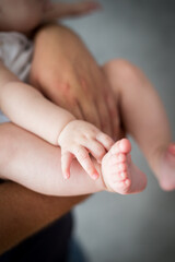 Rodzice trzymają w rękach swoje malutkie dziecko, stopy i rączki dziecka w dłoniach rodziców - obrazy, fototapety, plakaty