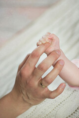Rodzice trzymają w rękach swoje malutkie dziecko, stopy i rączki dziecka w dłoniach rodziców