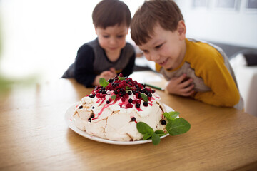 Beza z owocami lata i miętą, pyszne ciastko zjadane przez dzieci, chłopcy podziwiają domowe...