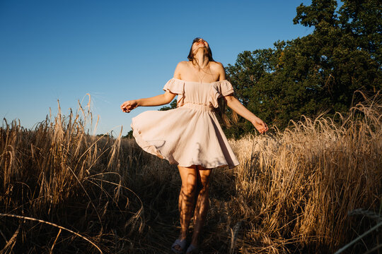 Connect with nature, Slow Down, Be Present, Get Into Your Senses. Peaceful alone Young woman in dress walking on wheat field at sunset summer day