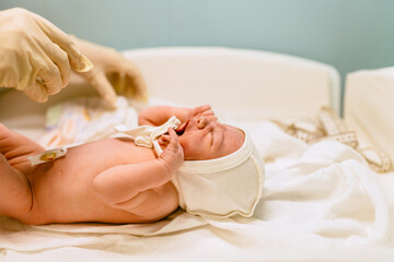 Fototapeta na wymiar Health care concept. Medical checkup. Doctor pediatrician examining new born baby boy in clinic. Nurse undressing crying infant baby boy.