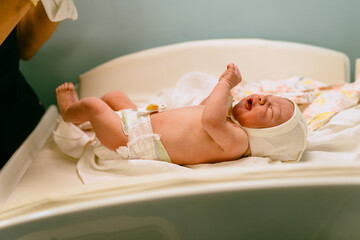 The nurse dresses crying just born baby. Newborn baby seconds after birth in hospital. Vertical...