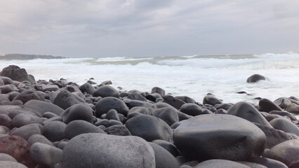 black rocks in a wave cloudy day