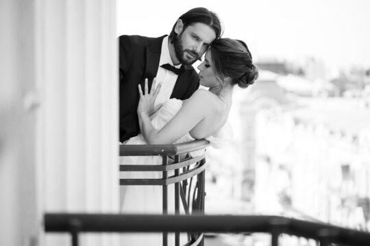 Happy and romantic couple in wedding dress kissing on the balcony overlooking the city
