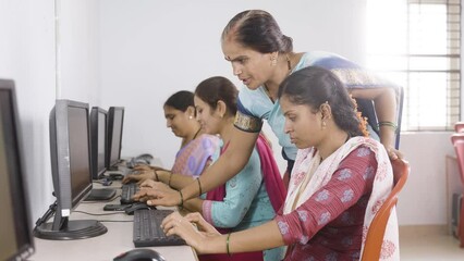 smiling teacher and student looking at camera while teaching computer class to woman's at village - concept of volunteer, self employment training and empowerment programs - Powered by Adobe