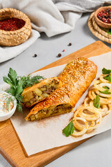 Meat pie with greens and onion on wood plate. Eastern food - beef pie with sesame. Eastern pastry with Minced meat.