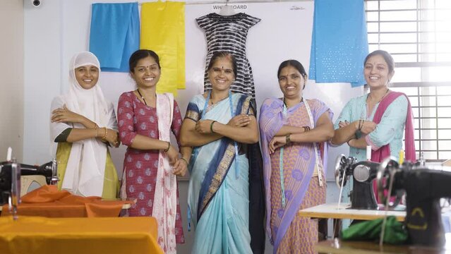 Team of confident woman woman workers at garment standing by arms crossed behind the sewing maching - concept of small business, community growth and development