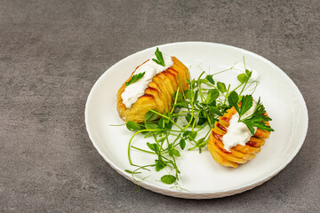 Baked accordion potatoes with fresh green pea sprouts.Traditional American food, homemade vegan diet