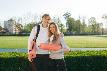 Young smiling sports couple, in sportswear, at the stadium looking at the camera, sports, healthy lifestyle