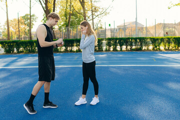 sporty young couple in the stadium talking to each other. The guy and the girl are preparing for training together. The concept of a healthy lifestyle