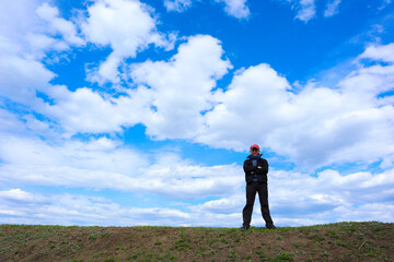 a man at the top against the background of a blue sky with clouds looks down