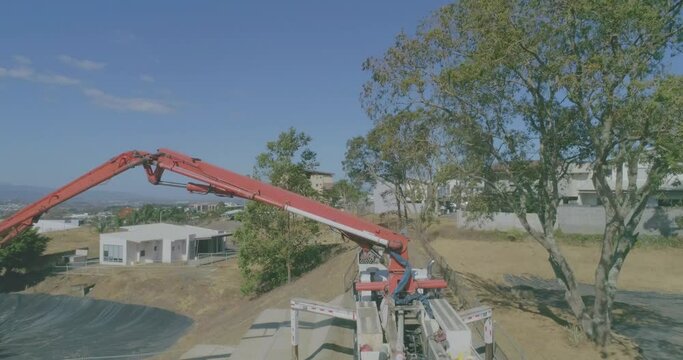 large concrete pump, drone shot, cement slab construction, cement mixer truck, cement ramp construction on lot, aerial video over residential