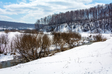 View of the Bolshaya Podikova River in spring with snow-covered banks