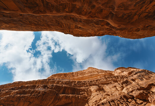 Looking up red sandstone canyon in Wadi Rum desert, blue sky with clouds above