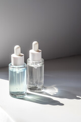 Two laconic bottles of cosmetic liquid in the rays of the harsh sun.