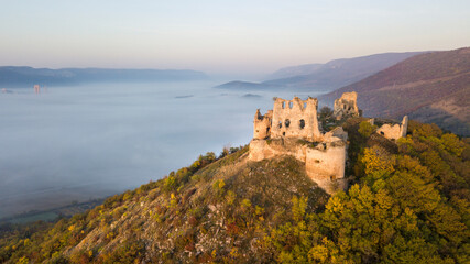 Fototapeta na wymiar the ruins of a medieval castle at sunrise over the fog