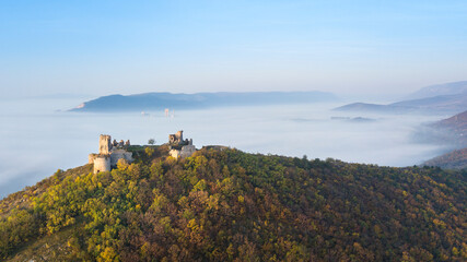 Fototapeta na wymiar the ruins of a medieval castle at sunrise over the fog