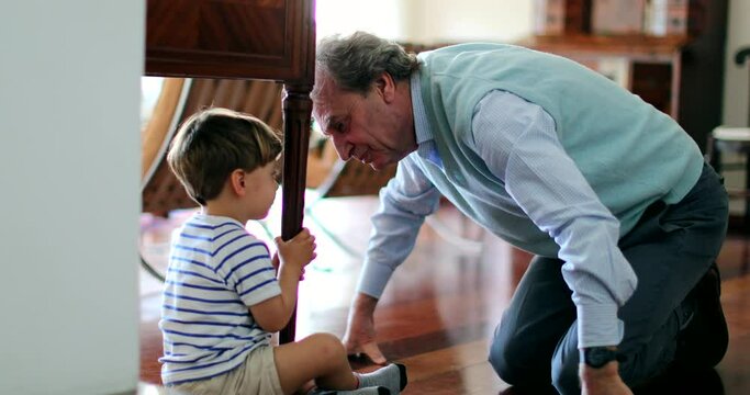 Empathic grandfather reaching out to emotionally hurt kid hiding underneath table