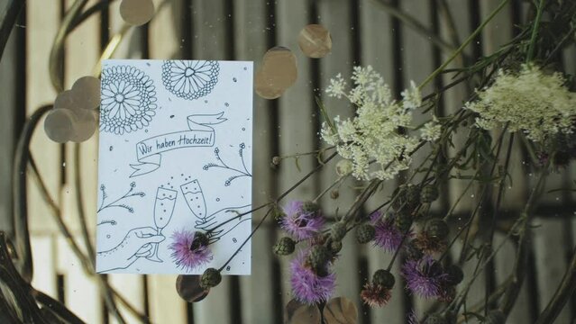 Wedding decor. Wedding invitation card composited with flowers on table. Part of the festive decor, Slow motion. 