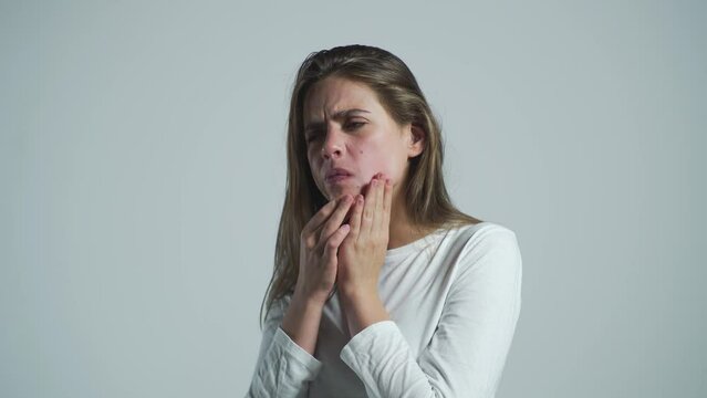 Girl suffering from toothache, tooth decay or sensitivity. Toothache, Woman with Tooth Infection. Woman suffering from toothache against gray background. Young woman suffering from toothache