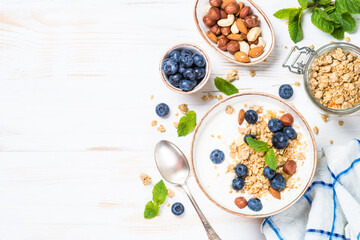Yogurt granola with fresh blueberries on white wooden table. Top view with copy space. Healthy...