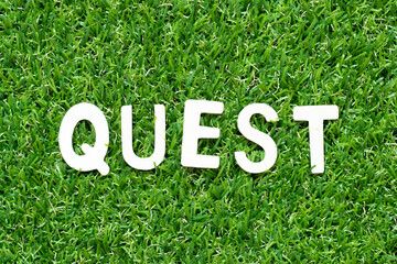 Wood alphabet letter in word quest on green grass background