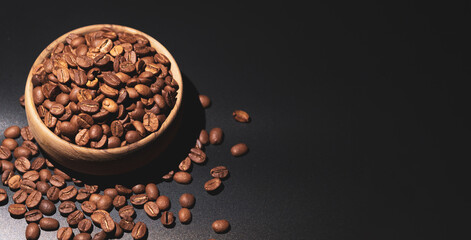 Coffee beans in bamboo bowl black background. Beautiful dark mode shot concept idea of lots of brown Turkish coffee beans. Large empty copy space for advertising banners and ad texts.