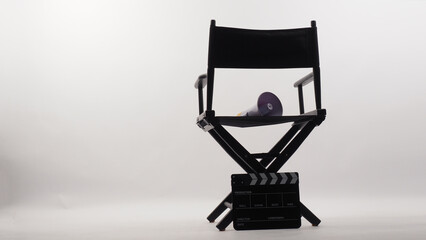 Back of director chair and megaphone on chair and clapper board on white background.