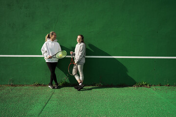 Mother and her teen daughter talking with each other on the tennis court