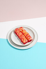 Baked Maki roll with tobiko caviar on ceramic plate. Hot sushi roll with tobiko and cheese topped on coloured background. Japanese menu concept. Hot maki sushi in modern style.