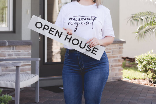 realtr in jeans holding an open house sign