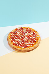 Italian pizza with ham and salami on coloured background. Meat pizza with ham, ketchup and mayonnaise in minimal style on blue colour. American pizza delivery concept with color backdrop