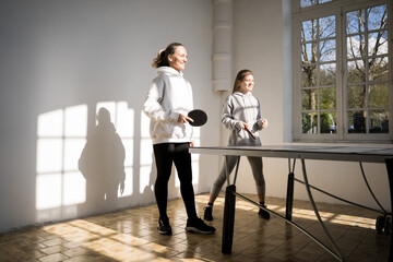 Caucasian mother and daughter playing together in table tennis