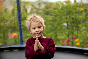Cute little boy with static electricy hair, having his funny portrait taken outdoors on  trampoline