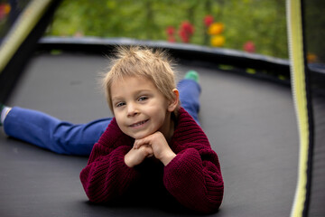 Cute little boy with static electricy hair, having his funny portrait taken outdoors on  trampoline