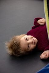 Cute little boy with static electricy hair, having his funny portrait taken outdoors on  trampoline