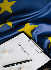Word SOLIDARITY is written on the paper. EU Flag. Closeup