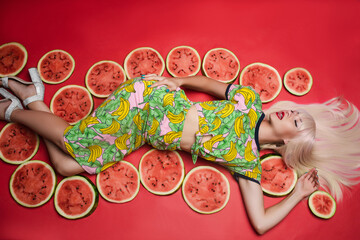 Sexy beautiful young woman lying on floor posing for photo shooting surrounded by watermelon