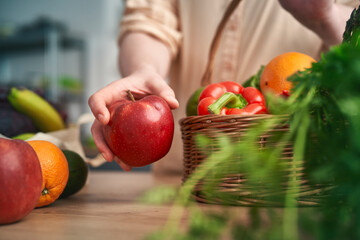 Woman holding apple and other fruits lying around © gpointstudio